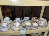 Full shelf showing all teacups, saucers, cream & sugar set with tray, teapot