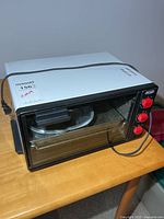 Front view showing glass door, interior tray, red control knobs, power cord