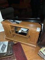 Front view of oak-finish corner TV stand with shelves and side doors