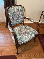 Front view of carved wooden armchair with floral upholstery
