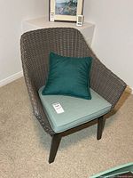 Front view of plastic wicker armchair with cushion and pillow