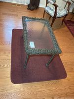 Plastic wicker coffee table on burgundy rug, full view
