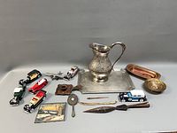 Group shot showing all items including pitcher, tray, model cars, airplanes, dishes, mirror, candle holder, thermometer, letter openers