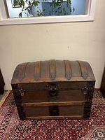 Full front view of wooden dome top trunk on rug