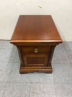 Front view of Broyhill wooden stand showing drawer, cabinet door and overall finish