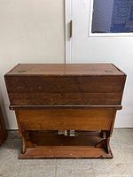 Front view of organ folded into case on stand