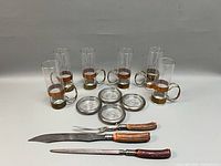 All items grouped: six glasses in holders, five coasters, carving knife, fork, sharpener