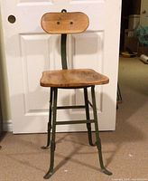 Full view of stool showing wooden seat/back and metal frame