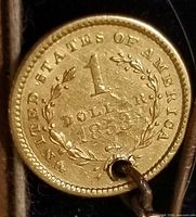 Reverse of 1853 United States $1 gold coin showing wreath and date, attached to stick pin