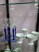 Group shot of four blue stem wine glasses and four porcelain cups with saucers