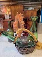 Overall lot showing demijohn, two green bottles, purple vase, ceramic figurine