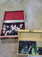 Wood box open showing pink/black pieces, yellow box with black pieces