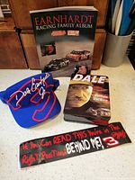 Group shot showing book, visor cap, DVD tin, bumper sticker