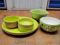 Assorted green melamine plates and bowls plus ceramic bowls on floor