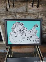 Front view of framed teal line drawing showing entire artwork