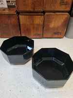 Two black octagonal serving bowls side by side
