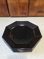 Stack of six black octagonal plates showing uniform design