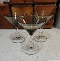 Front view of three smoked glass martini glasses