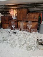 Group shot of 20 assorted clear glass barware pieces on countertop
