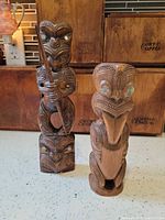Both wooden tiki statues standing side by side on countertop