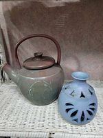 Teapot beside pierced blue lantern on wicker surface