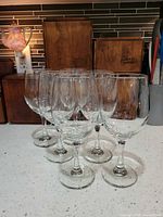 Six clear stemmed wine glasses grouped on countertop