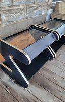 Two black Z-shaped tables stacked side by side on porch