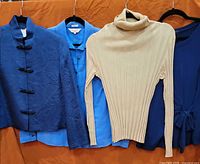 Four tops hanging: jacket, blouse, sweater, wrap top