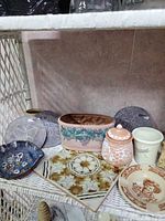 Group view of all pottery pieces and slate trivets on shelf