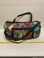 Front view of colorful patchwork Bali Agung duffle showing handles and strap