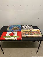 All four board game boxes on table: Trivial Pursuit DVD Pop Culture, Rummikub, Canada-opoly, Full House