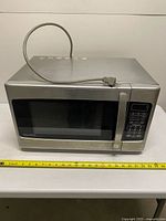 Top angled view showing full microwave, power cord, stainless finish