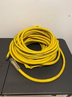 Full coil of yellow hose with nozzle visible