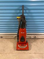 Full view of red Kenmore upright vacuum with hose