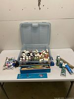 Open storage case showing numerous paint bottles, brushes tray, rulers and extra tubes