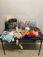 Full table view of assorted yarn, fabric samples, crochet pieces, plastic flowers