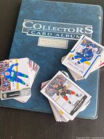 Blue Collectors Card Album binder with three loose stacks of NHL cards.