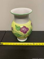Full view of vase front with floral design and measuring tape indicating height