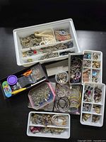 Overview of organizers filled with jewelry pieces, Dior box, craft supplies