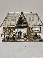 full view of brass and glass house with miniatures inside