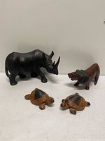 Group shot of rhinoceros, lion and two turtle carvings