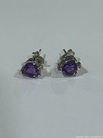 Front view of both earrings showing heart-shaped purple stones and diamond accents