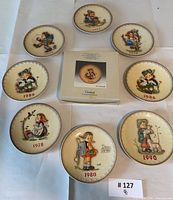 Group shot of eight loose plates and one boxed plate showing years and designs