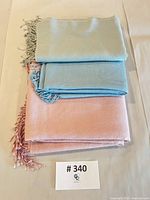 Three pastel scarves stacked showing colors and fringe