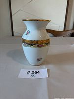 Front view of porcelain vase showing gold rim, broad gold band, floral motifs