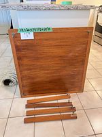Square teak tabletop underside with four detached legs displayed