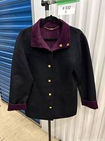 Black side of reversible coat showing plum collar, cuffs and gold buttons