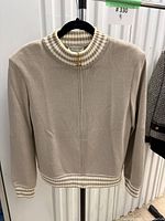 Front view of beige zip-front St. John Sport sweater on hanger