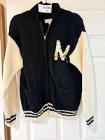 Full front view of black and cream wool sweater on hanger