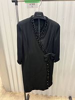 Full view of black wrap dress on hanger